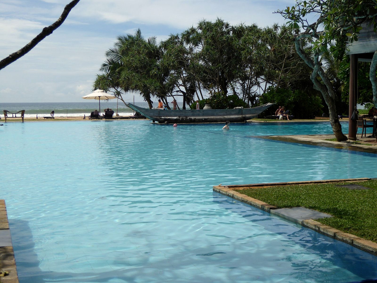 Hotel pool beside the sea under palm trees